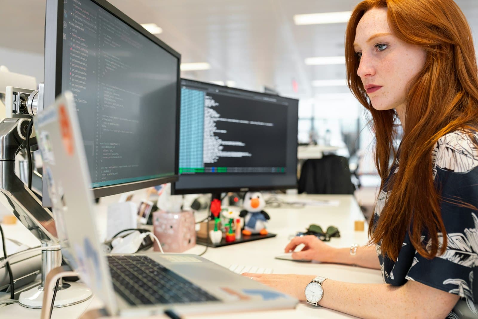 Engineer working through code on a dual-monitor workstation