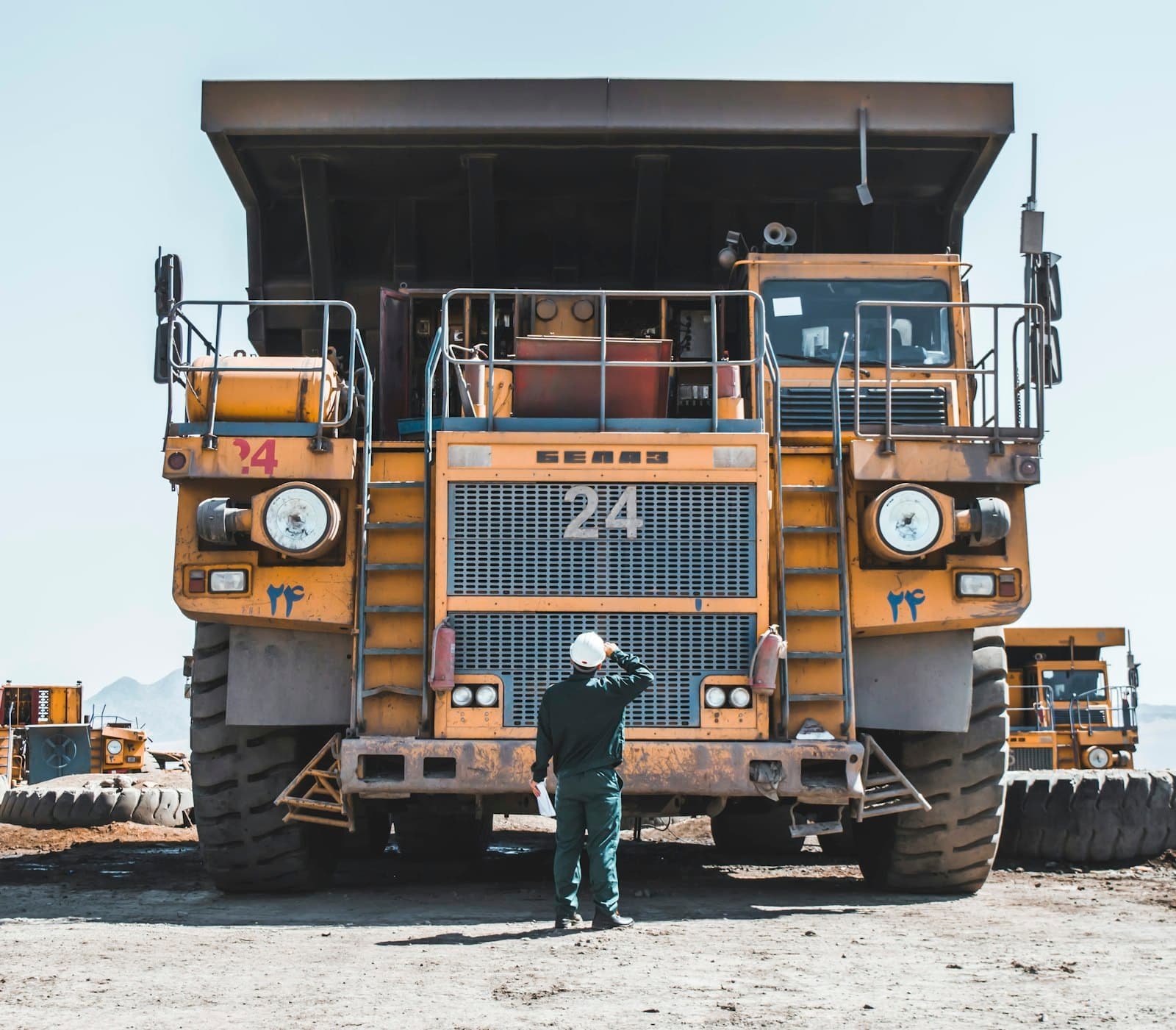 Operator standing in front of a haul truck in a heavy-equipment yard