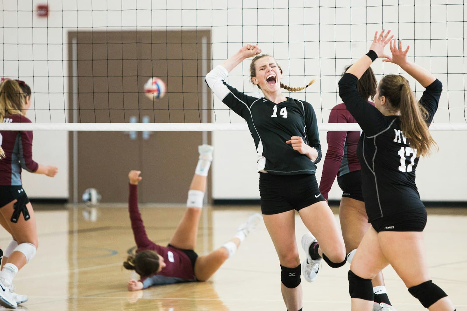 Volleyball players celebrating a point on an indoor court