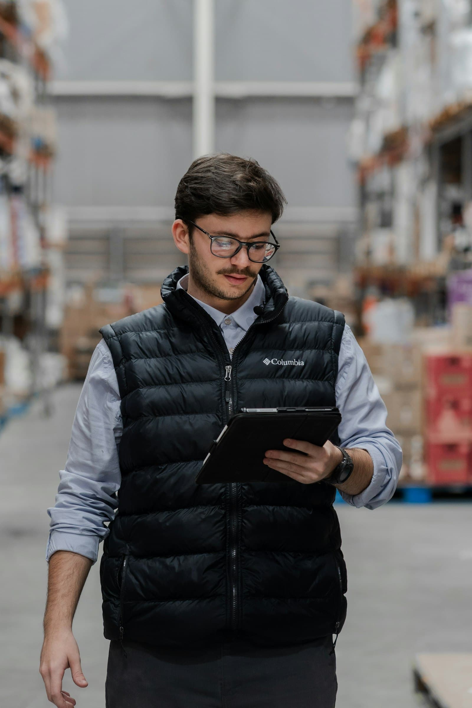 Warehouse manager checking stock on a tablet between racks