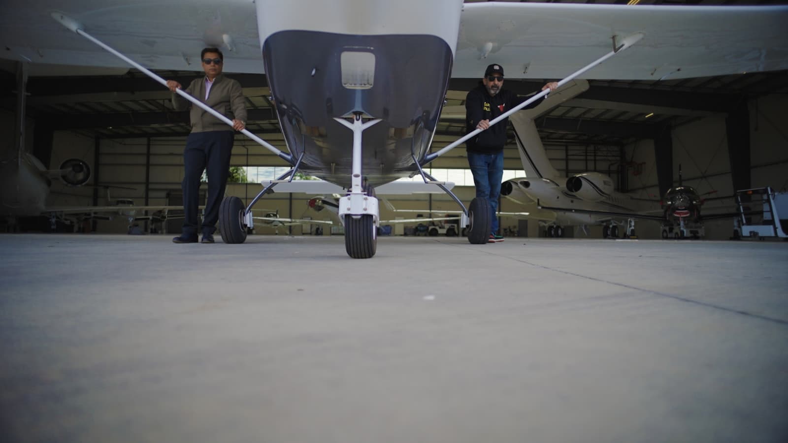 Two technicians beside a light aircraft in a maintenance hangar