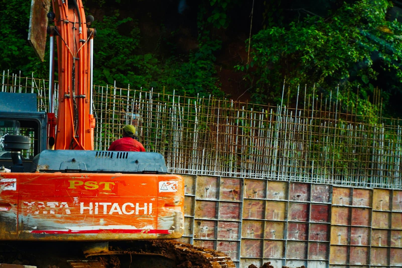 Worker beside an orange excavator on an active construction site