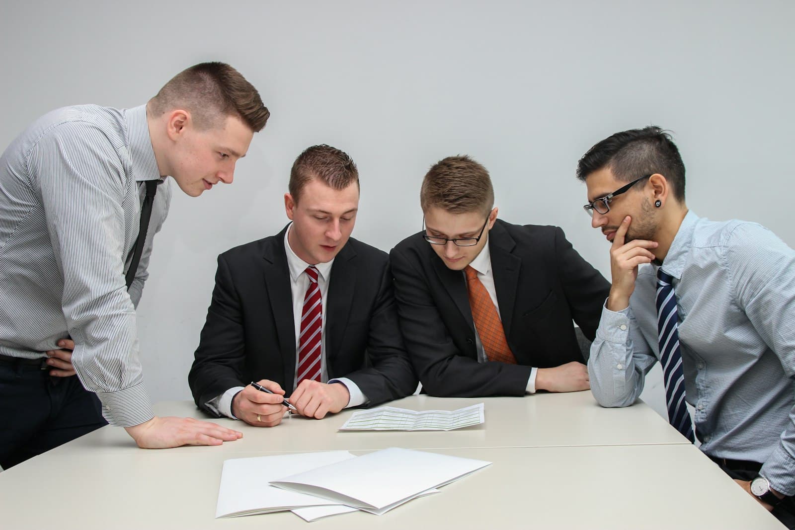 Four colleagues in shirts and ties reviewing case documents at a conference table